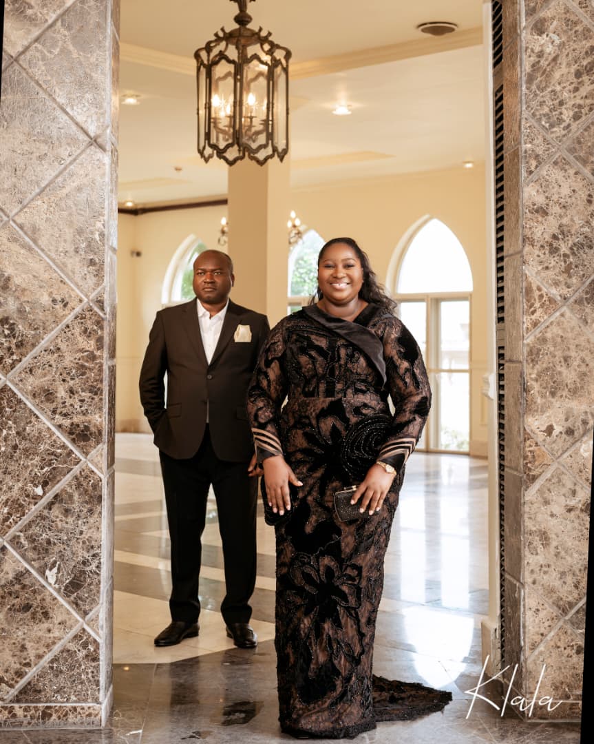 Dr AjokeSings and her husband standing together in a marble archway, dressed for an evening out