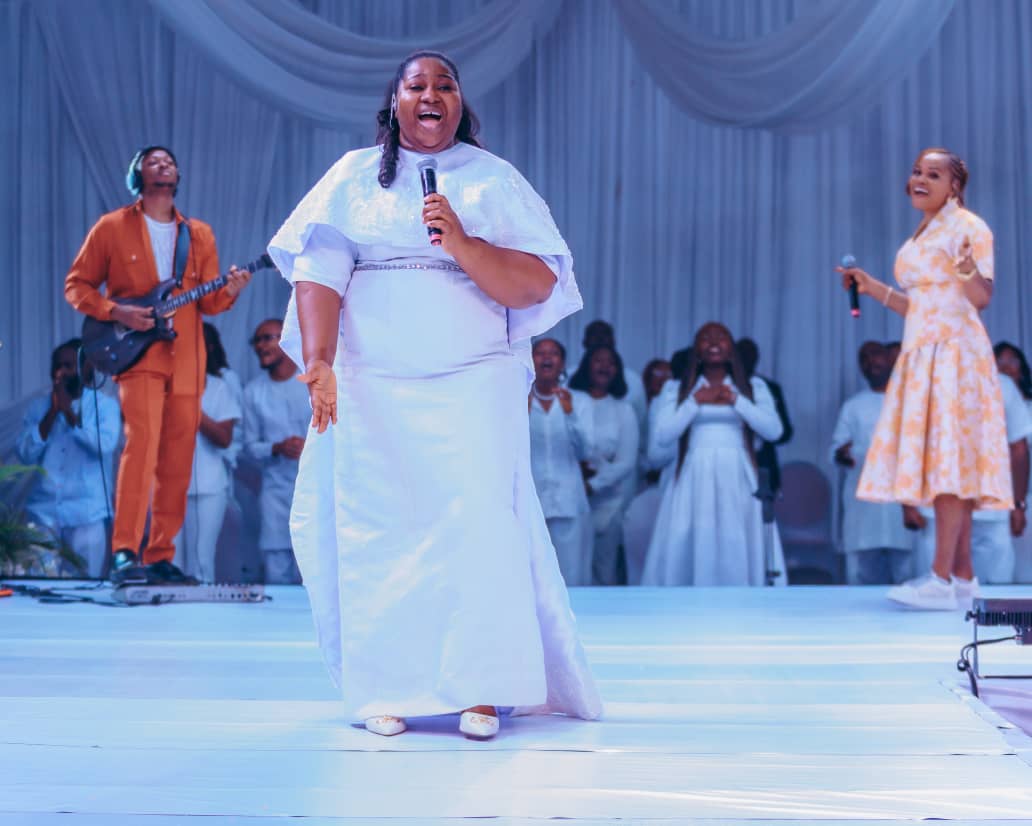 Leading worship on a white stage with the full band and choir behind her